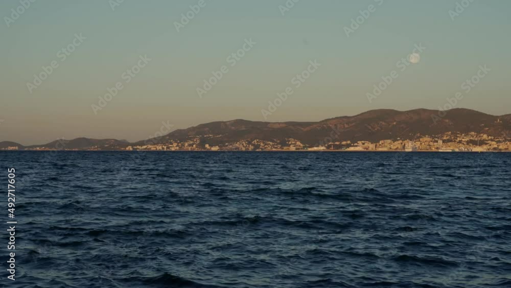 Full moon over Palma de Mallorca and its bay in the early morning. With deep blue ocean waves overseeing mountains. 4k. Full moon over Palma de Mallorca and its bay in the early morning. With deep blue ocean waves overseeing mountains. 4k.