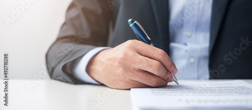 man signing on contract documents after reading, man holding pen and approve on business report. Contract agreement, law and deal concepts photo