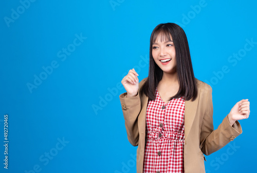 Portrait of beautiful young Asian girl model long hair in casual summer clothes smile, happy and enjoying in studio isolated on blue background.