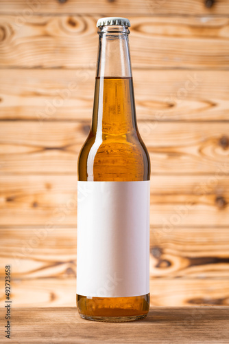 Blank label on the beer bottle on wooden background.