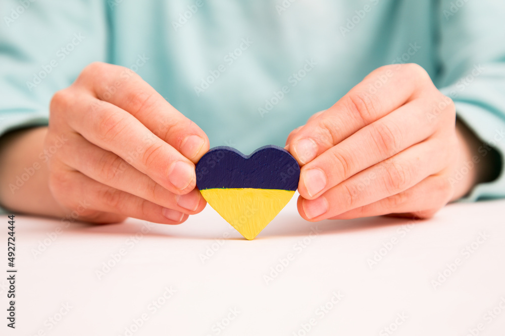 High angle view of child hands holding ukraine flag painted heart High angle view of child hands holding ukraine flag painted heart