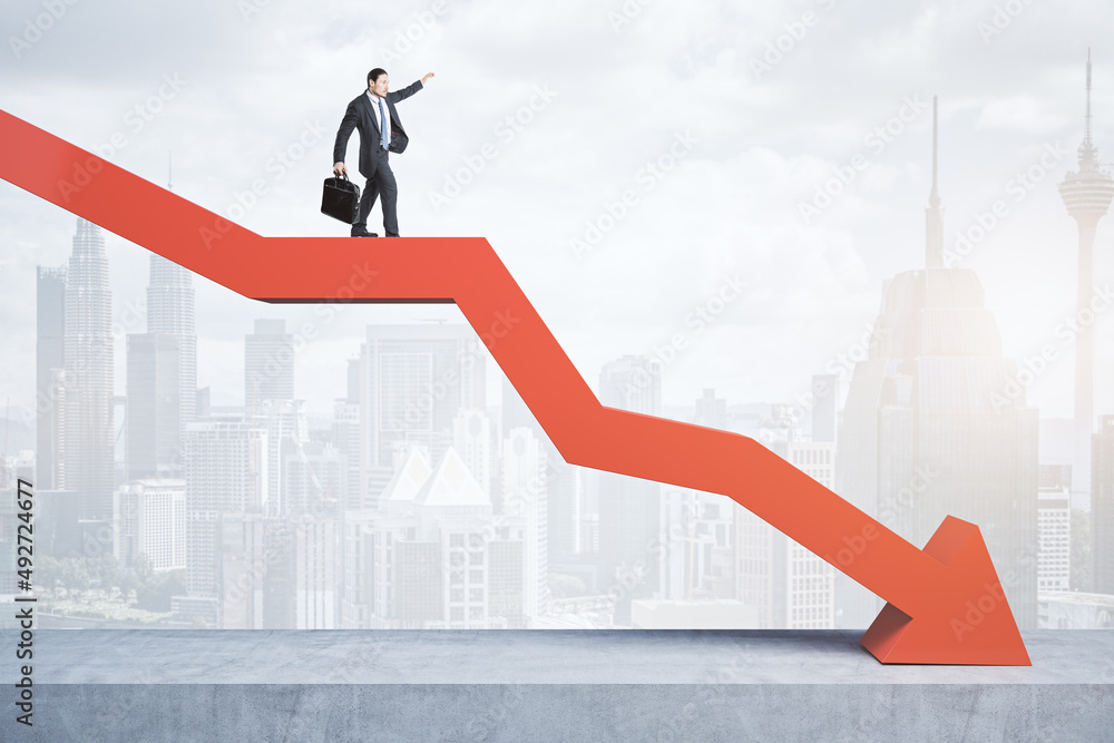 Business man standing and balancing on abstract red downward chart arrow on light city background with mock up place. Down, drop, finance and crisis concept. Business man standing and balancing on abstract red downward chart arrow on light city background with mock up place. Down, drop, finance and crisis concept.