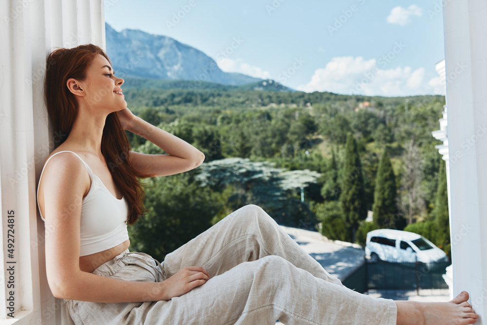 beautiful woman with long hair on an open balcony Green nature summer day Relaxation concept