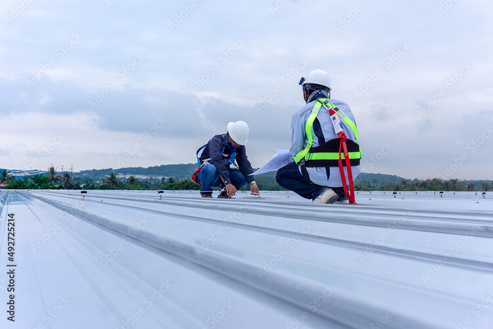Two engineers wearing full safety body harness working inspection on roof top - obrazy, fototapety, plakaty 