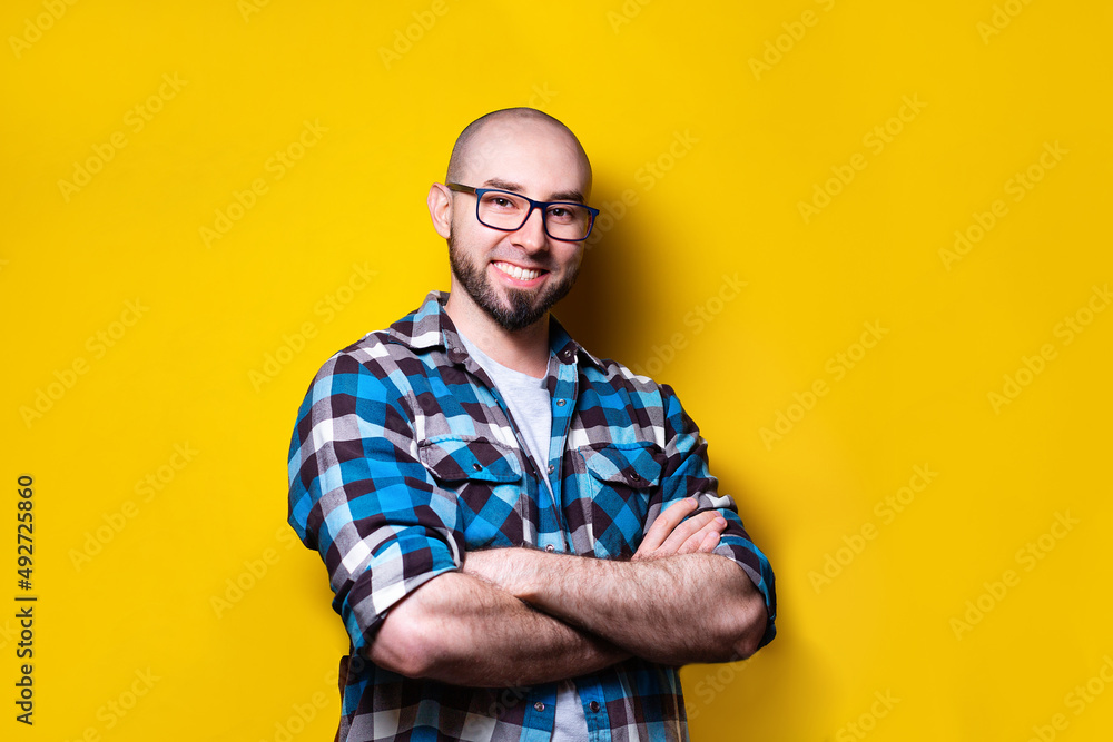 Portrait of a smiling young handsome man, arms crossed, posing on a yellow background. Copy space. The concept of success Portrait of a smiling young handsome man, arms crossed, posing on a yellow background. Copy space. The concept of success