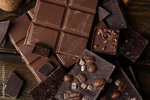 Foto Broken chocolate bars on dark wooden background
