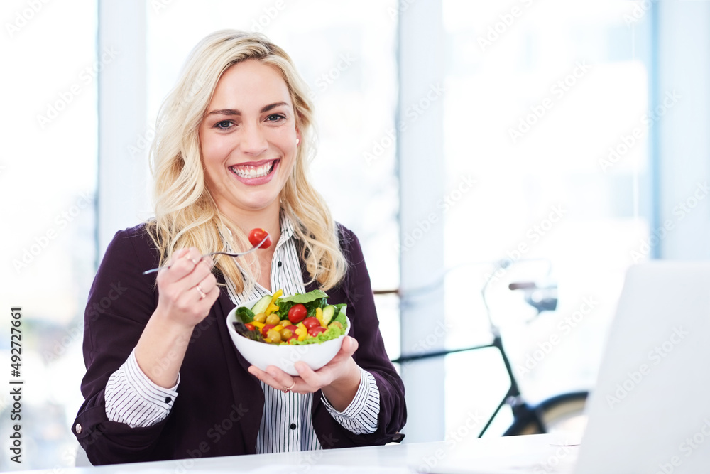 Balancing work with a healthy lifestyle. Cropped portrait of an attractive young businesswoman eating a salad while working in her office. Balancing work with a healthy lifestyle. Cropped portrait of an attractive young businesswoman eating a salad while working in her office.