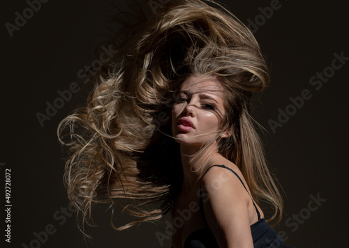 Beautiful woman with shiny hair. Beauty face of young girl, movement hair. Sexy female model posing in studio. Vogue style portrait closeup.