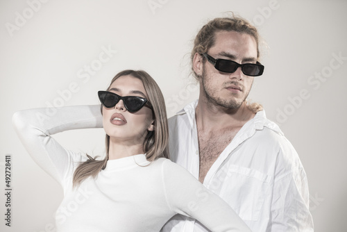 Couple in fashion black sunglasses. Young couple posing with sunglasses. Studio shot on gray background.