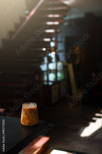 Ice coffee on a black table with cream being poured into it showing the texture and refreshing look of the drink © pariwatpannium