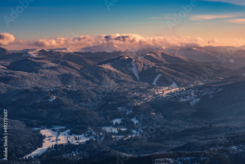 Aerial view of beautiful moutains and valley in the winter landscape, with ski resort slopes and magical sunset light