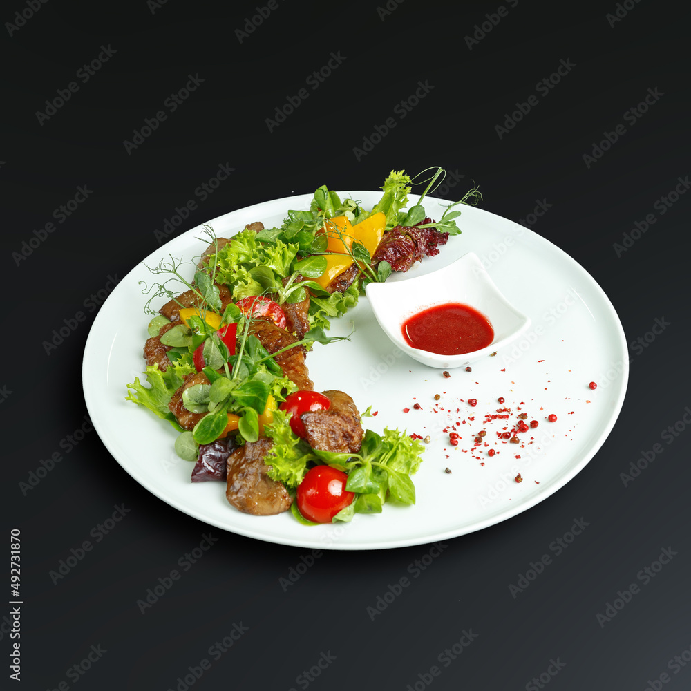 traditional dishes of European cuisine, delicacy, banquet snack. culinary dishes on a white plate on a black background. restaurant service