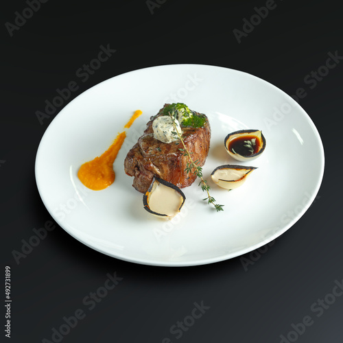 traditional dishes of European cuisine, delicacy, banquet snack. culinary dishes on a white plate on a black background. restaurant service photo