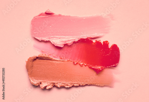 Lipstick burgundy peach orange brown balm lip gloss swatch isolated on beige background photo