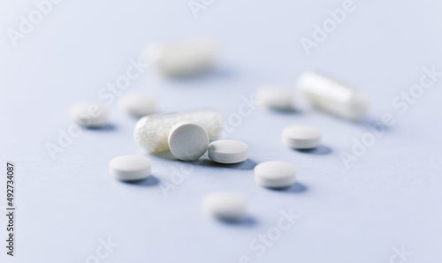 Vitamin C tablets and capsules on bright paper background. Soft focus. Close up. Copy space. 