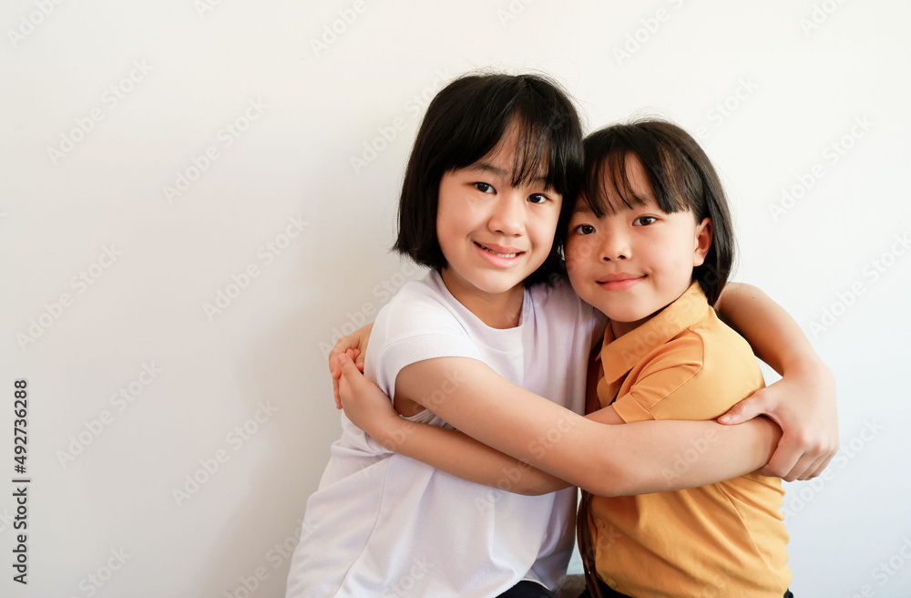 Two girls sitting next to each other hugging each other. showing their connected faces on a white background. Two girls sitting next to each other hugging each other. showing their connected faces on a white background.