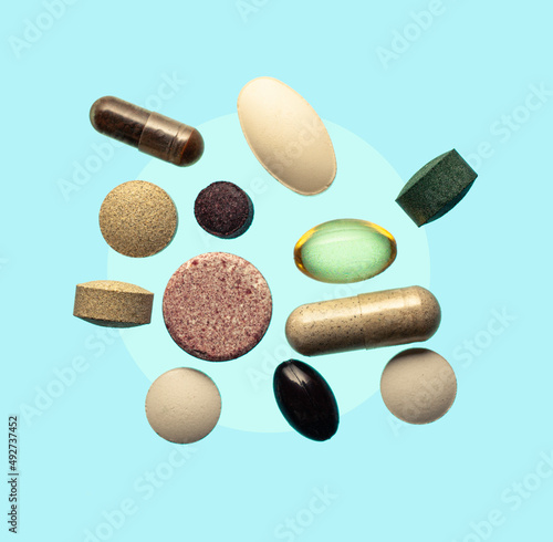 Flying vitamines minerals fish oil dietary supplements pills on a blue gradient background