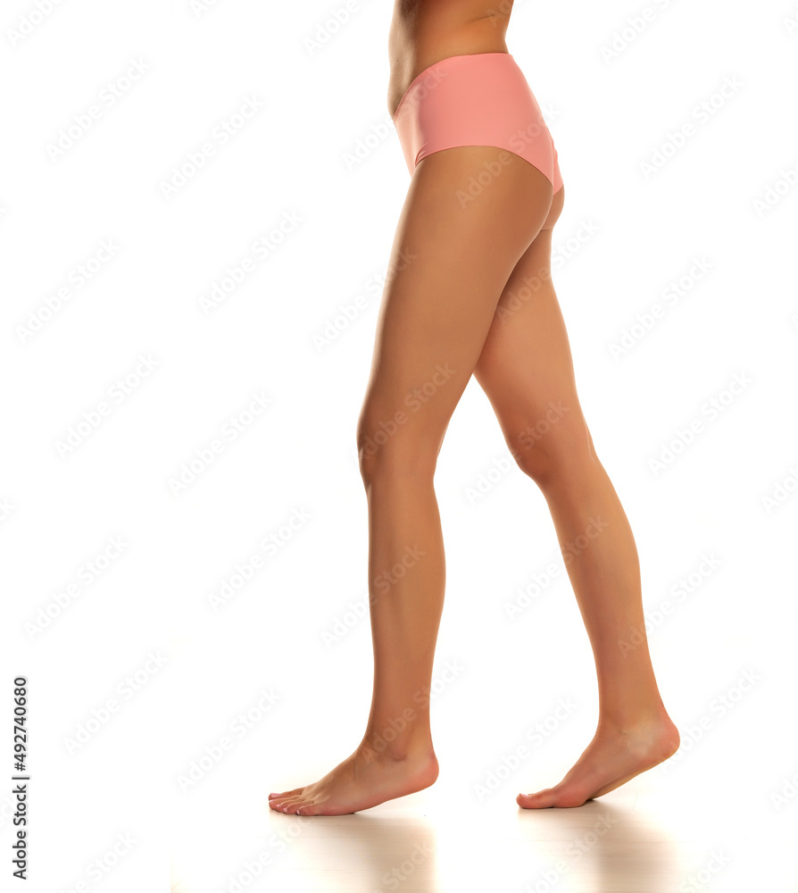 side view of pretty female bare legs in pink panties standing on white side view of pretty female bare legs in pink panties standing on white