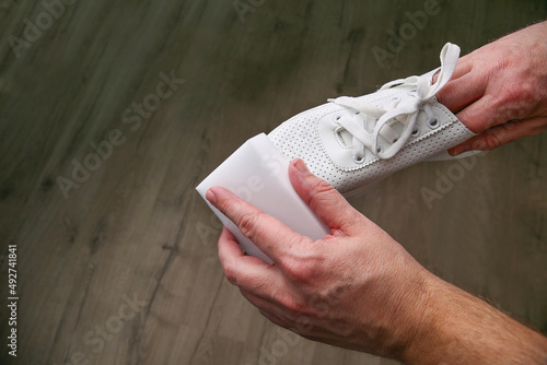 A man cleans white sneakers with  melamine sponge. photo