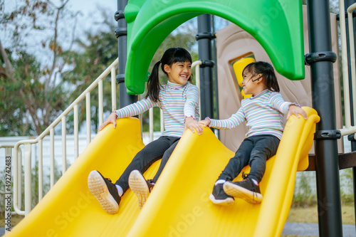 Two girls play slides in the playground.