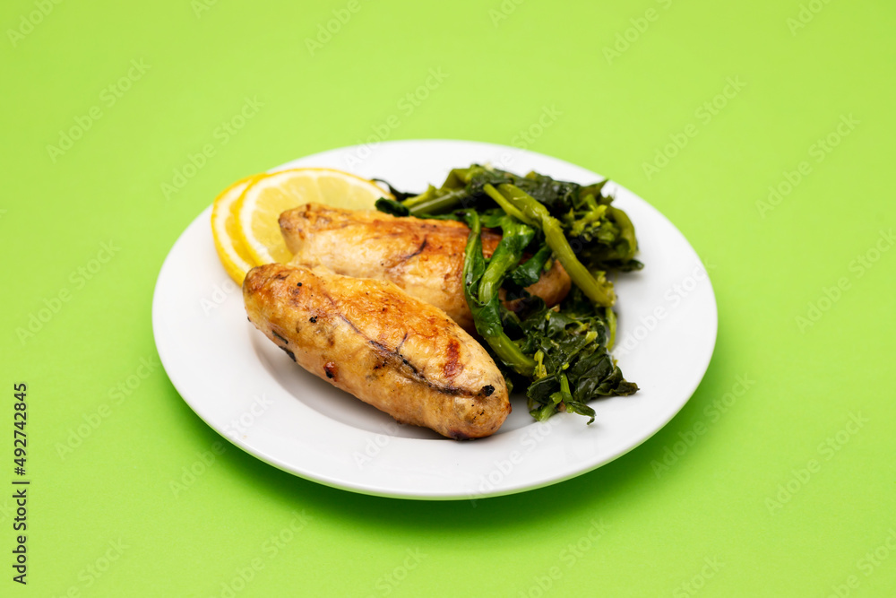 Grilled caviar cod fish with greens and fresh lemon on white small plate. Grilled caviar cod fish with greens and fresh lemon on white small plate.