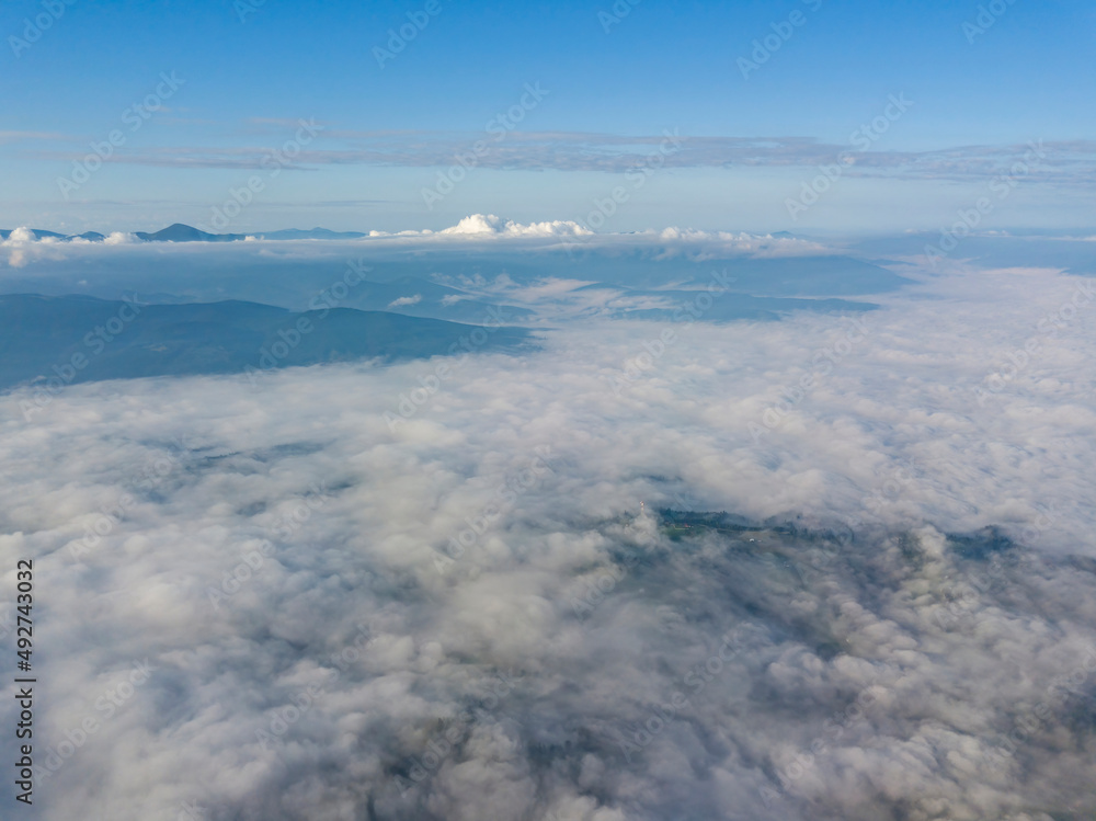 High flight above the clouds in the mountains. Aerial drone view.