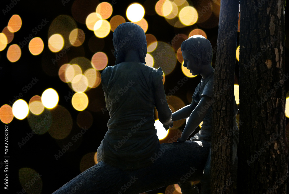 silhouette couple of young person statue sitting together on large tree brunches in the night with bokeh light background,