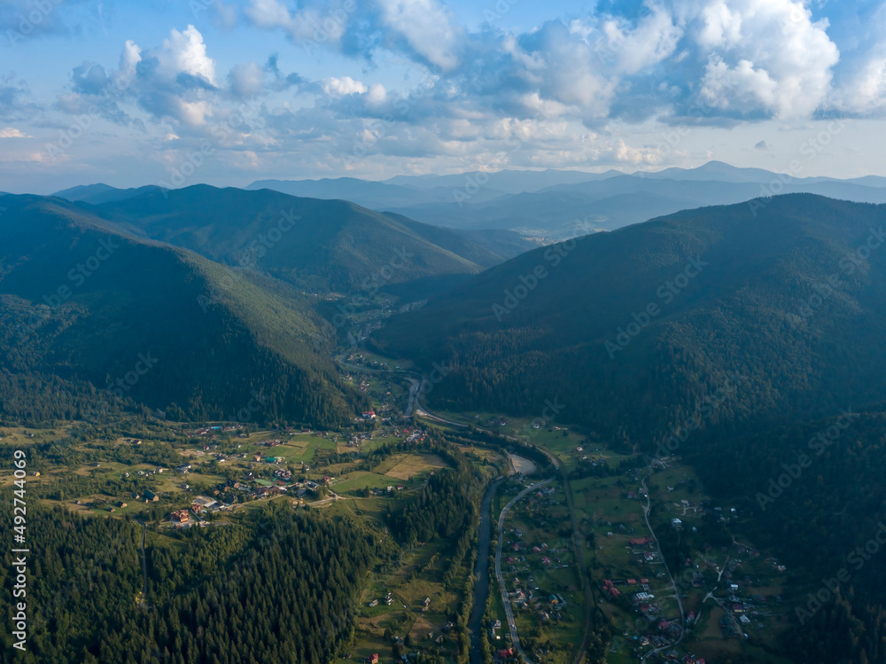 Green slopes of Ukrainian Carpathian mountains in summer. Cloudy day, low clouds. Aerial drone view.