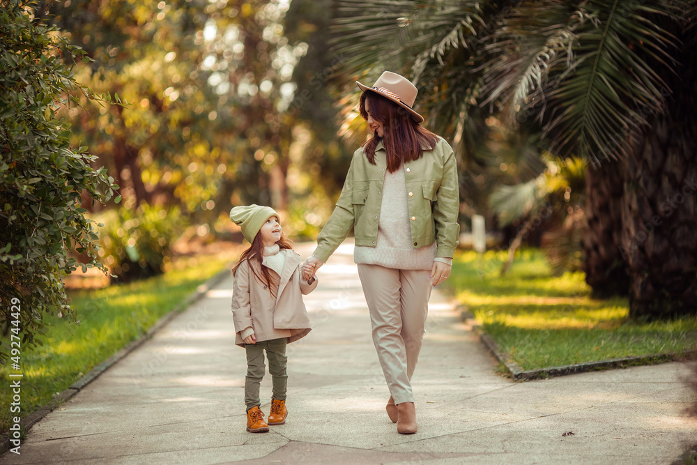 Fototapeta premium red-haired mother and daughter are walking in the park. family leisure in the city