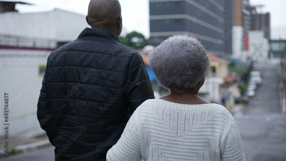 An aged son walking with elderly mother in 80s outside in urban street going for a walk An aged son walking with elderly mother in 80s outside in urban street going for a walk