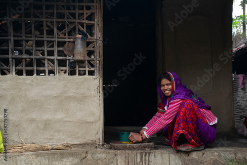 indian woman grinding spices for making food in kitchen photo