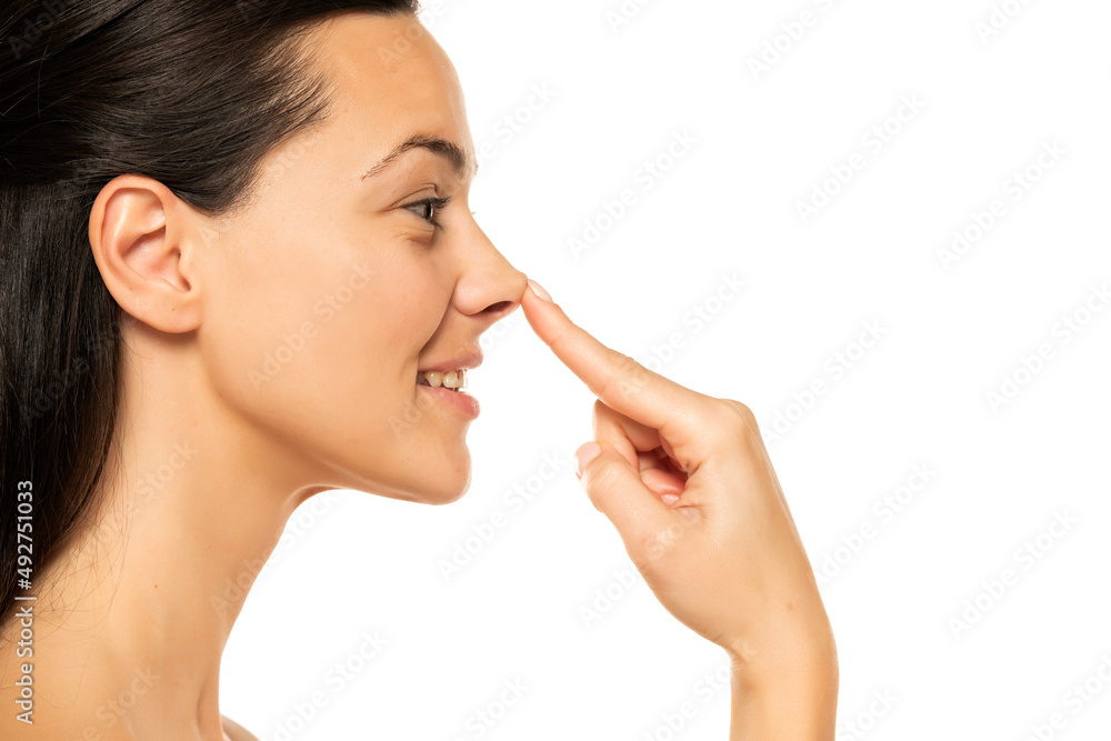 young happy woman touches her nose with her finger on a white background young happy woman touches her nose with her finger on a white background