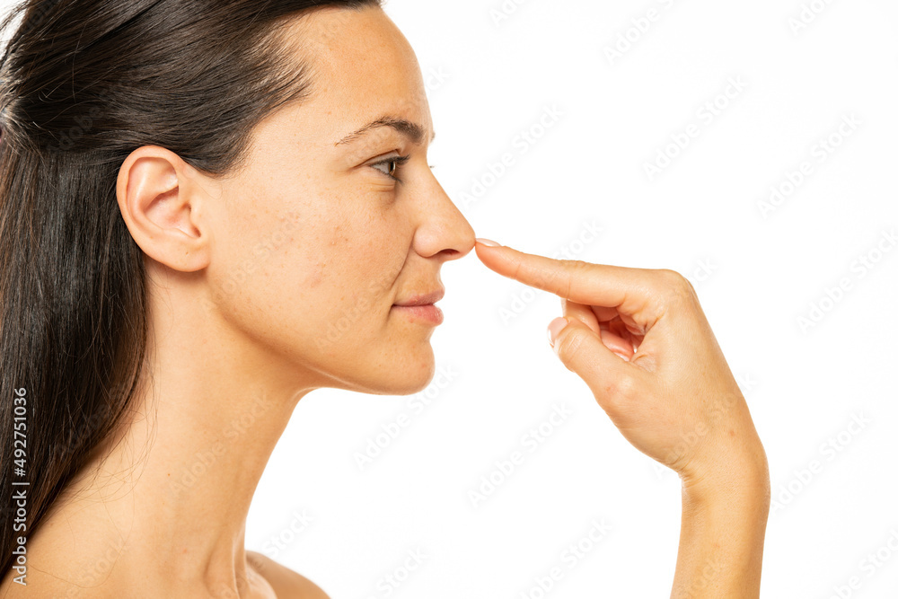 young woman touches her nose with her finger on a white background young woman touches her nose with her finger on a white background