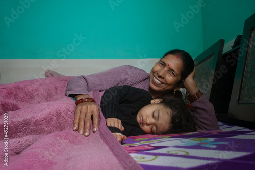 Grandmother and her little granddaughter sleeping together in bed. India photo