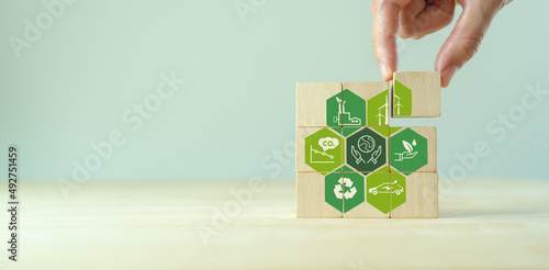 Save of earth, saving environment, net zero emissions concept. Green business and sustainable development. World earth day. Hand puts wooden cubes with clean energy icon standing on eco friendly icon.