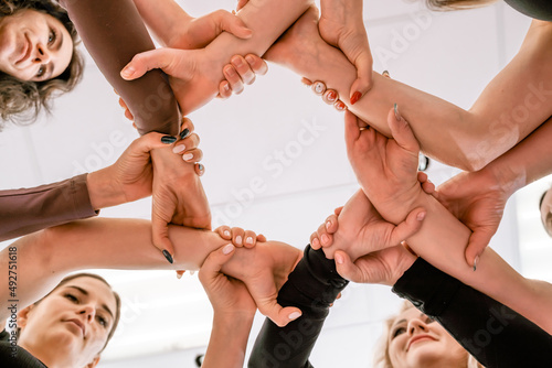 Team of people holding hands. Group of happy young women holding hands. Bottom view, low angle shot of human hands. Friendship and unity concept