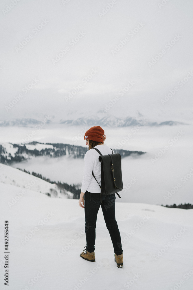 Woman standing in mountain. Cold weather, snow on hills. Winter hiking.