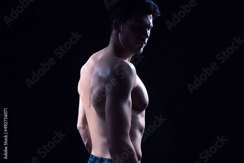 Modern Youth Lifestyle. Contrast Portrait of Confident Thinking Caucasian Bodybuilder Athlete Man Posing With Naked Torso Against Dark Background.