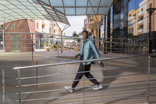 Cool African American guy walking near contemporary building and looking away