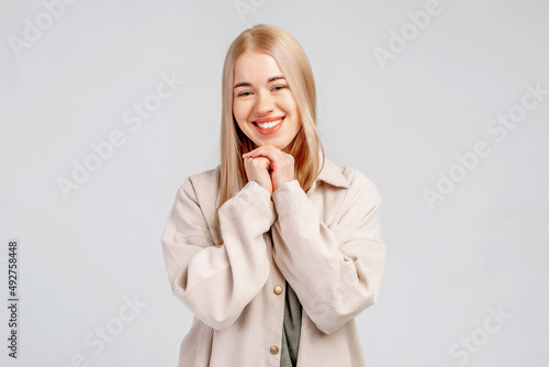 Lovely girl makes gratitude gesture presses palms to chin feels touched pleased by compliments says thank you expresses thankfullness  gray background. Body language and real feelings concept