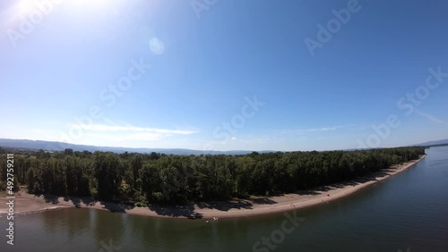 Drone flight over portlant river. The shot approaches a group of trees on the river bank. photo