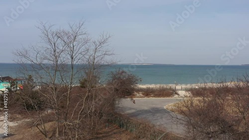 An aerial view of Meschutt Beach on Peconic River, Long Island, NY. The drone camera boom up from the ground, taken on a beautiful day with one person walking to a car by the beach. photo