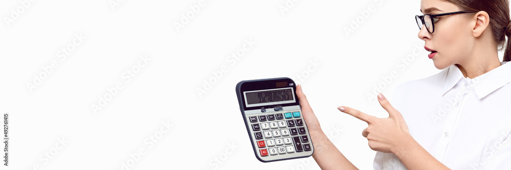 Banner format surprised female accountant in a white shirt with glasses holding a calculator in her hands points her finger at him Banner format surprised female accountant in a white shirt with glasses holding a calculator in her hands points her finger at him