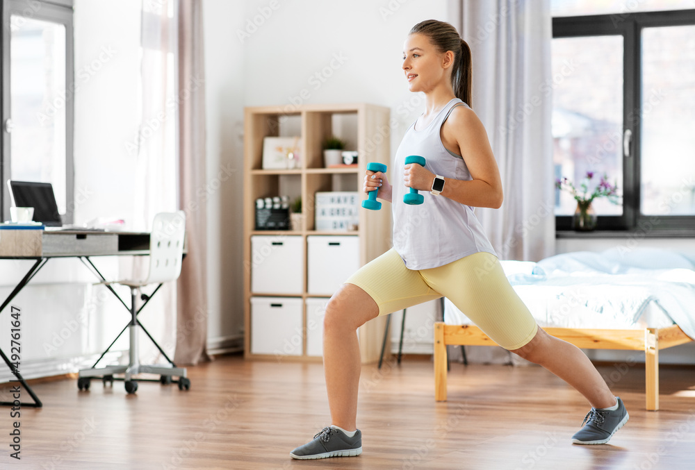 fitness, sport and healthy lifestyle concept - happy teenage girl with dumbbells exercising at home