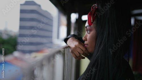 Foto A pensive black girl standing at home balcony looking out in contemplation