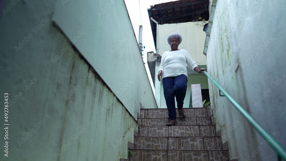 An African woman going down the stairs opening home gate and leaving house to urban sidewalk street