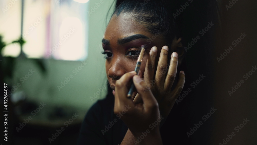 A young woman applying make-up in front of mirror A young woman applying make-up in front of mirror