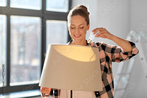 Tablou pe pânză moving, electricity and repair concept - woman changing light bulb in floor lamp