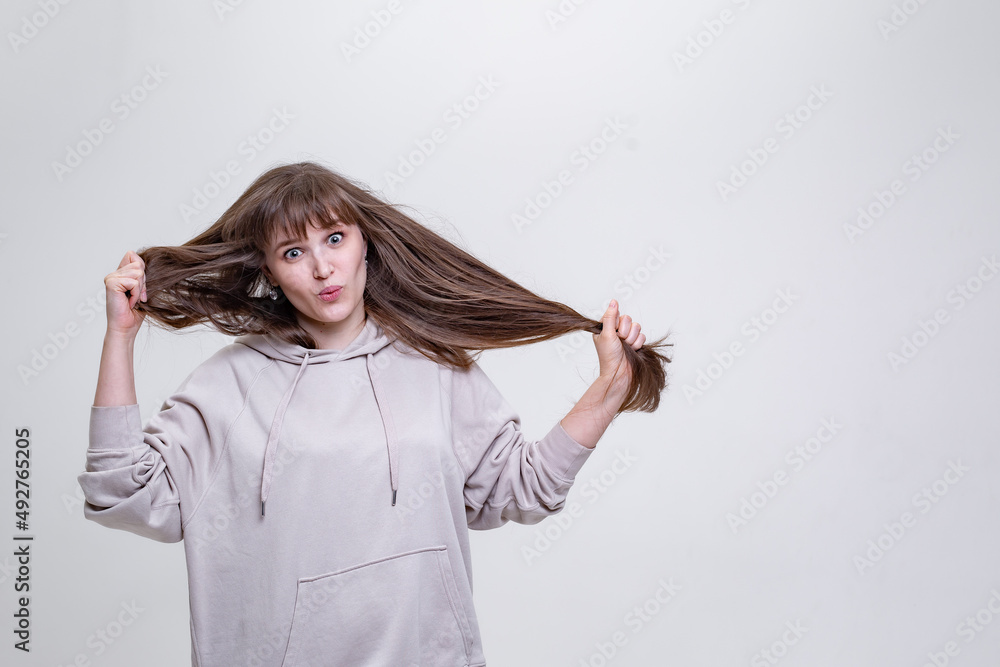 a pretty blonde girl with long hair pulls her hair, makes a grimace a pretty blonde girl with long hair pulls her hair, makes a grimace