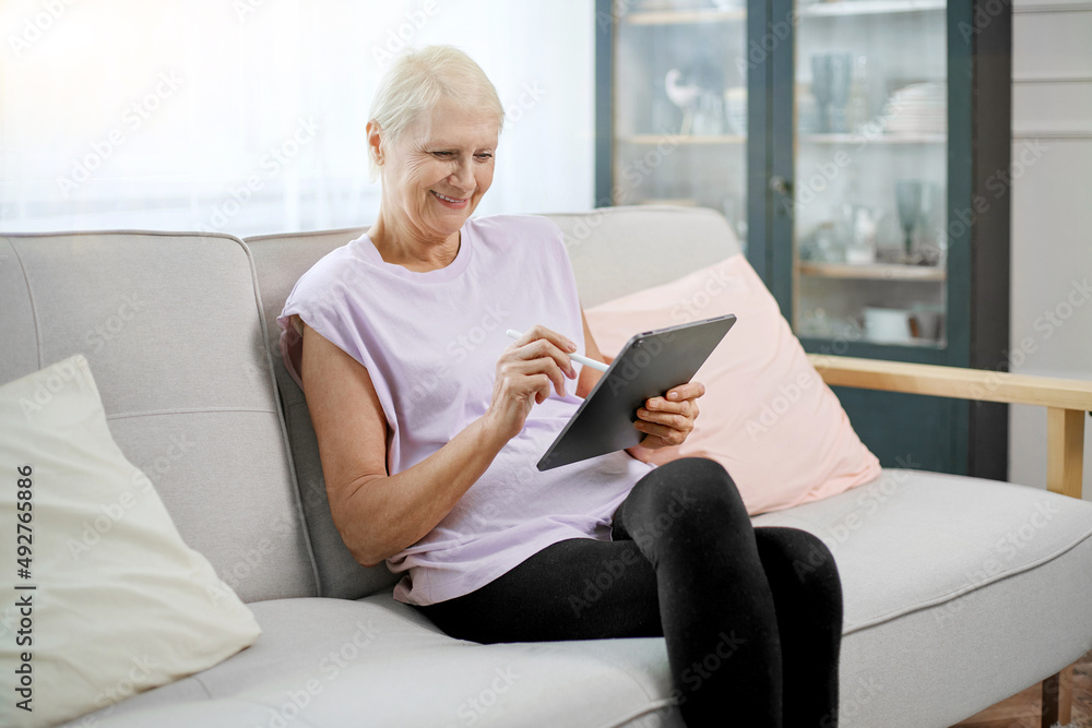 elderly woman sitting in a yoga pose in front of an open laptop. elderly woman sitting in a yoga pose in front of an open laptop.